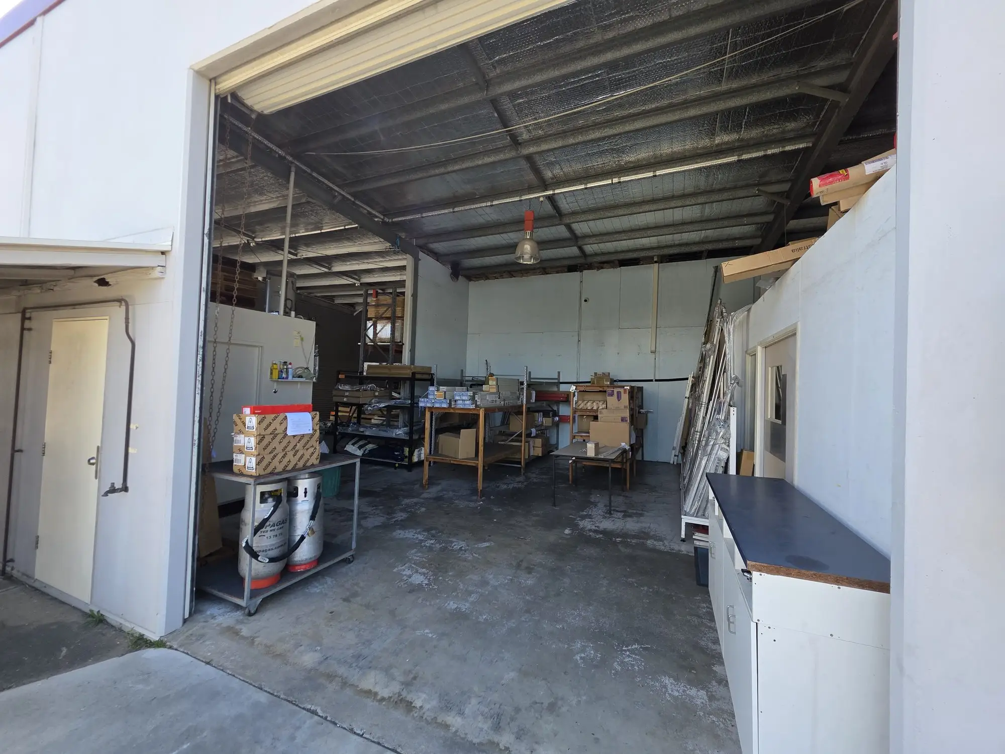 The open roller door of the despatch and receiving bay, with cartons on a trolley.